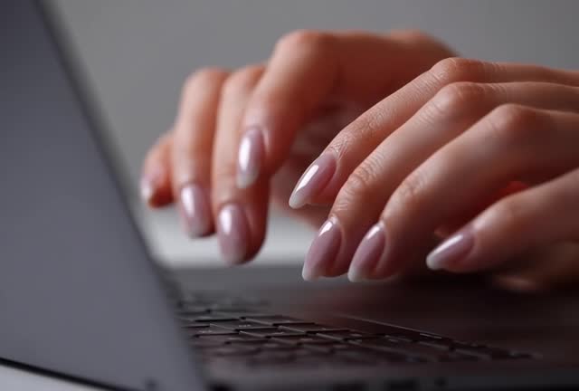 Close-up of Hands Typing on Laptop with Stylish Nails