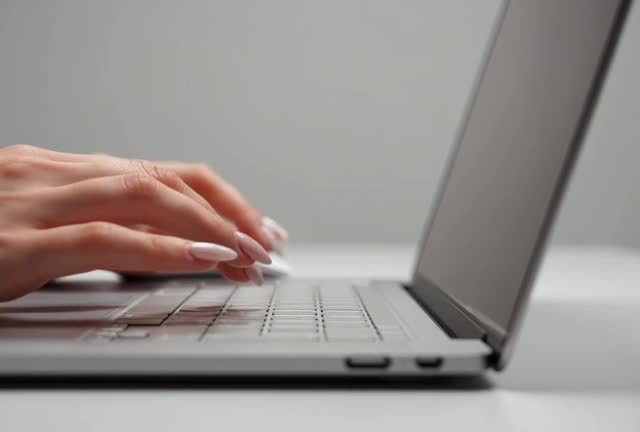 Close-Up Footage of Hands Typing on a Laptop Keyboard